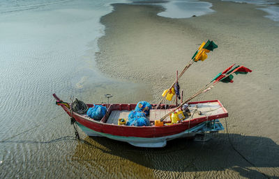 High angle view of boat with flags moored at beach during sunny day