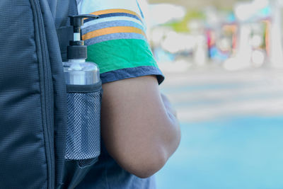 Midsection of boy with backpack and bottle