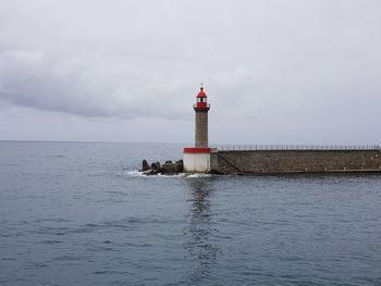 Lighthouse by sea against sky