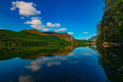 Scenic view of lake and mountains against blue sky