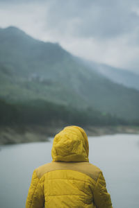 Rear view of woman looking at lake against mountains