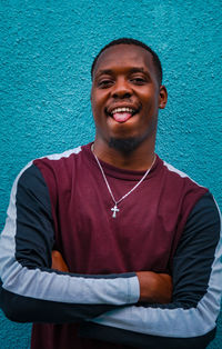 Portrait of smiling young man standing against wall