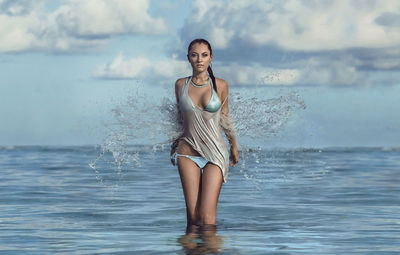 Young woman standing at beach against sky