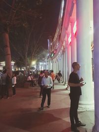 Group of people walking in illuminated city at night