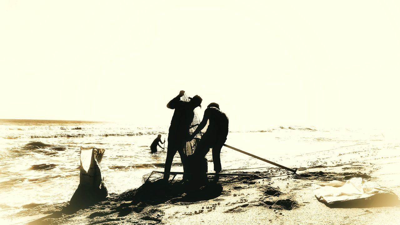 MEN ON BEACH AGAINST SKY