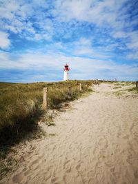 Lighthouse on beach against sky