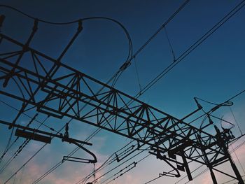 Low angle view of silhouette electric cables against blue sky during sunset