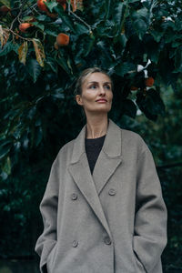 Portrait of young woman standing against plants