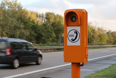 Road sign by street against sky