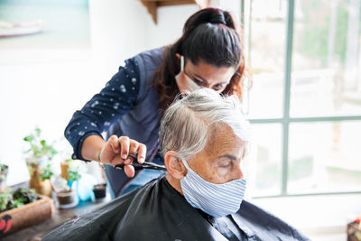 Beautician treating hair of customer at home