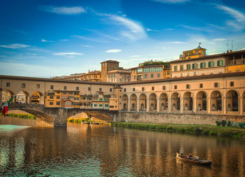 Bridge over river by buildings against sky in city