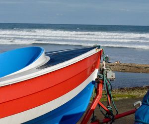 Close-up of boat moored on beach against sky