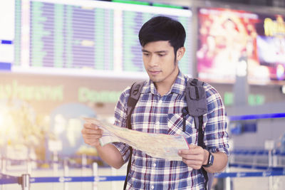 Man reading map while standing at airport terminal