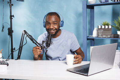 Portrait of young man using laptop at desk in office