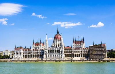 Buildings by river against sky