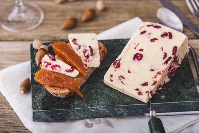 Wensleydale cheese with cranberries, red wine, honey, nuts, raisins on wooden cutting board. 