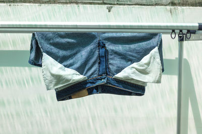 Jeans drying on clothesline against wall