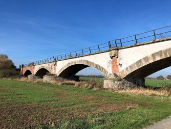 Low angle view of arch bridge on field against sky
