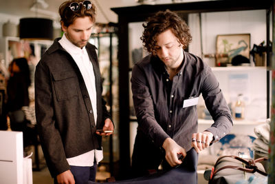 Salesman showing luggage bag to male customer at retail store