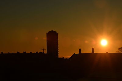 Silhouette buildings against orange sky