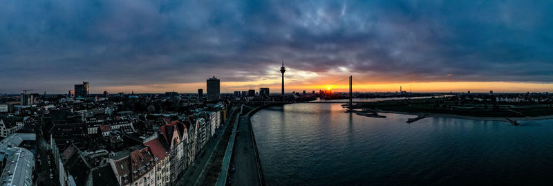 Panoramic view of river and buildings against sky during sunset