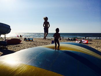 Siblings jumping on bouncy castle at beach