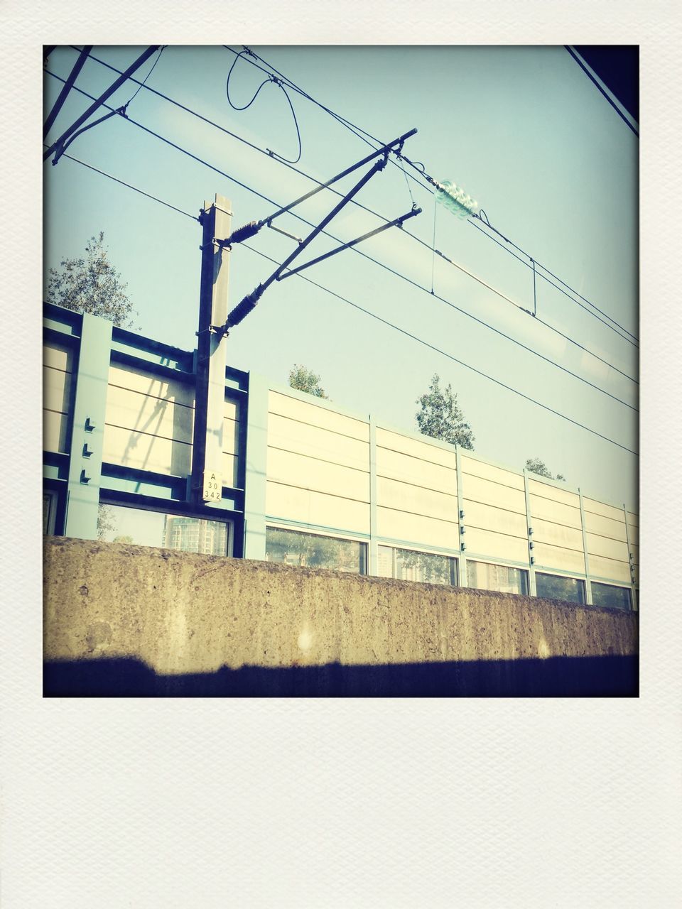 architecture, built structure, building exterior, transfer print, power line, clear sky, auto post production filter, electricity pylon, fuel and power generation, sky, window, day, power supply, house, no people, building, outdoors, low angle view, cable, fence