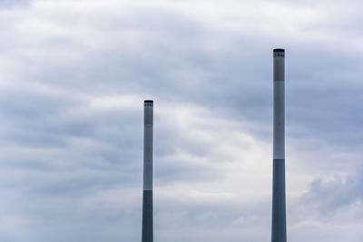 Low angle view of smoke stacks against sky