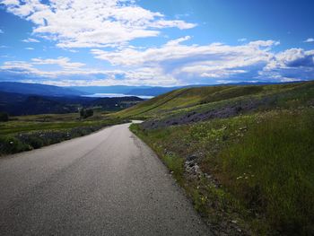 Road leading towards mountains against sky