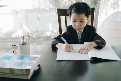 Young man using mobile phone while sitting on table