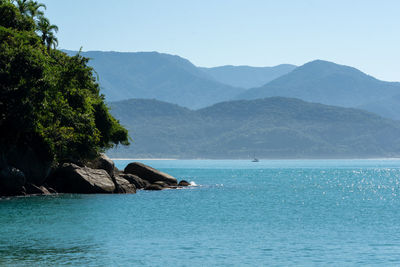 Scenic view of sea and mountains against clear sky