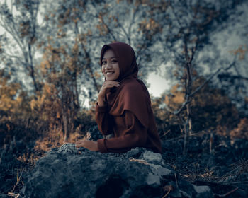 Side view of woman looking away while sitting on rock