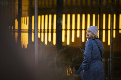 Young woman walking outdoors and using phone