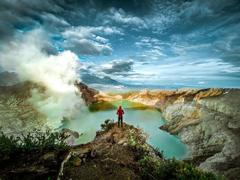 Man standing on rock against sky