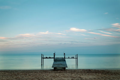 Lifeguard hut on beach against sky during sunset