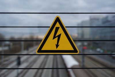 Close-up of warning sign on metal against sky