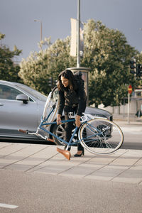 Woman with umbrella on car in city
