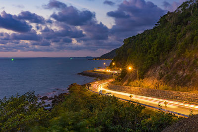 High angle view of illuminated road by sea against sky