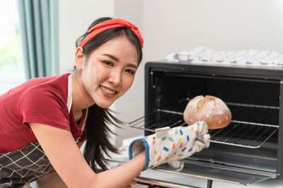 Portrait of chef putting bread in oven