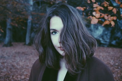 Close-up portrait of beautiful woman against autumn trees