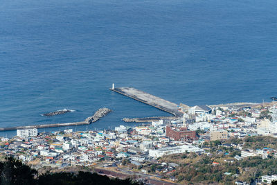 High angle view of buildings by sea against blue sky