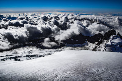 Scenic view of cloudscape seen through snow covered mountain