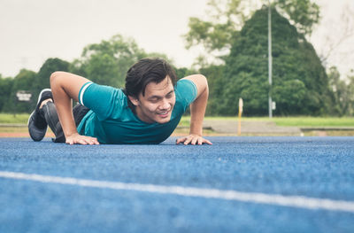 Full length of tired young man lying on sports track