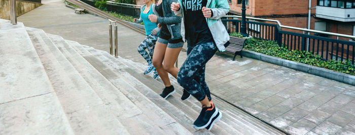 Young women friends training running up stairs in town