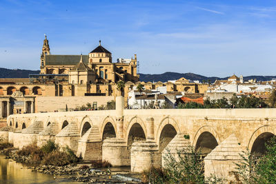 Arch bridge over river against buildings in city