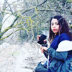 Portrait of young woman using mobile phone while standing in winter