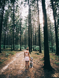 Young woman standing on tree trunk in forest