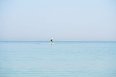 Man doing e foiling around people paddle boarding