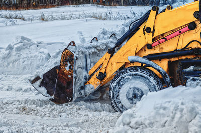 Yellow tractor cleans up snow from road. cleaning and cleaning of roads in city from snow in winter