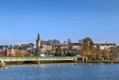 Buildings at waterfront against blue sky